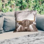 Outdoor weather-resistant cushion featuring a Scottish Highland cow design in gold with horns, 50x50 cm.